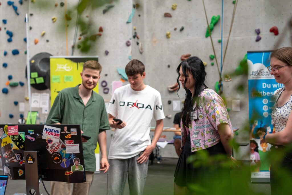 Junge Menschen stehen vor einem Messestand